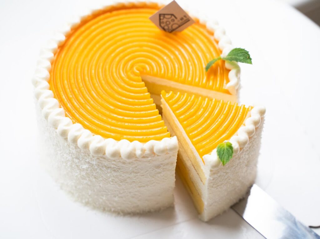 a mango cream cake with mango cream and leafy decoration on top.