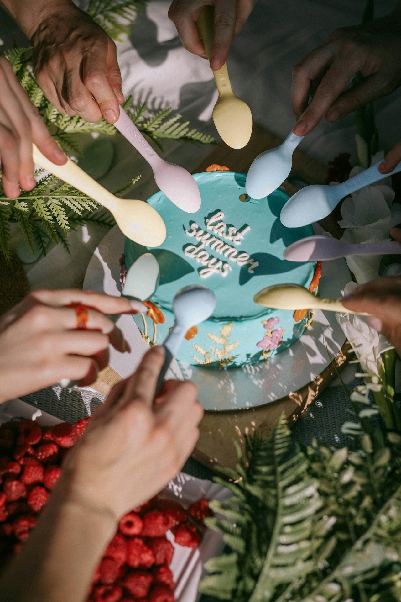 this image shows a cake for summer and a group of people holding a spoon each trying to have the cake.